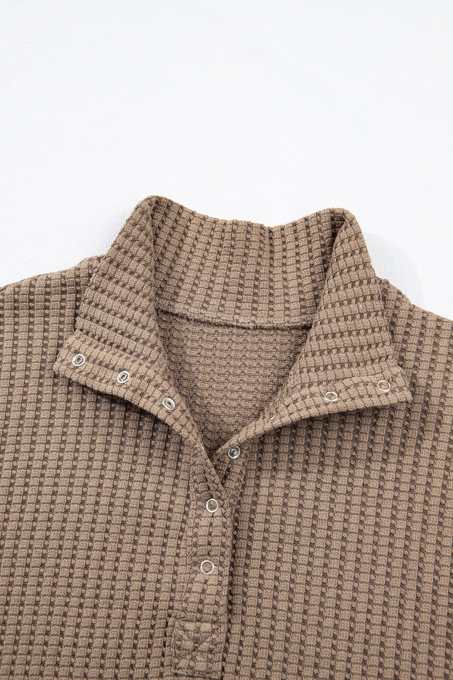 Woman wearing a Mocha textured waffle knit pullover with snap collar, relaxed long sleeves, and ribbed cuffs with white pants.