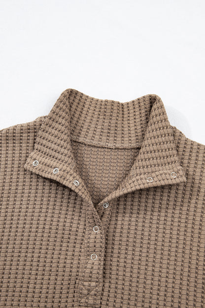 Woman wearing a Mocha textured waffle knit pullover with snap collar, relaxed long sleeves, and ribbed cuffs with white pants.