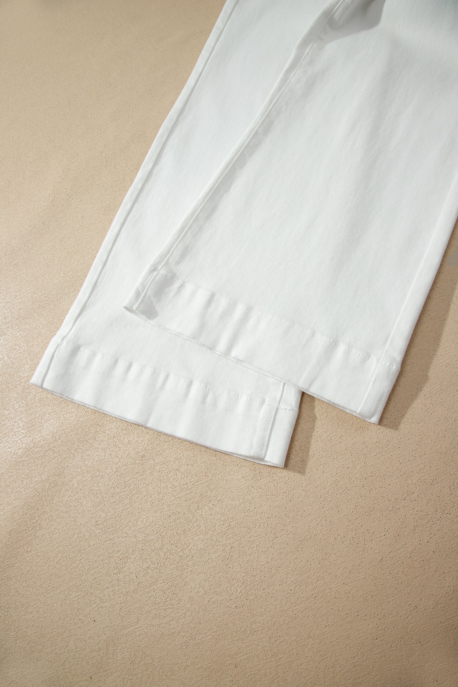 White high rise wide leg jeans with double-button waistband, front pockets and cropped hem.
