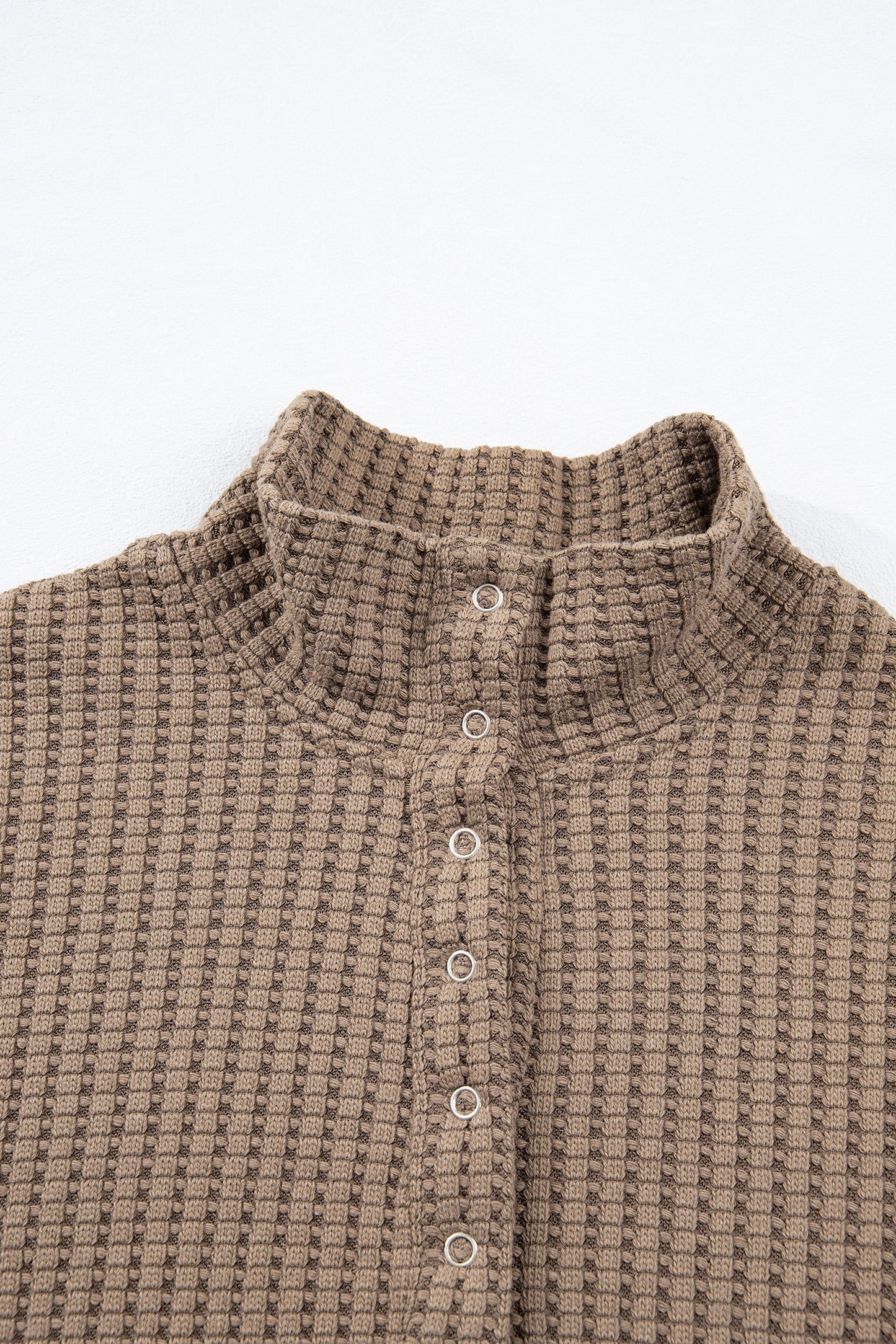 Woman wearing a Mocha textured waffle knit pullover with snap collar, relaxed long sleeves, and ribbed cuffs with white pants.