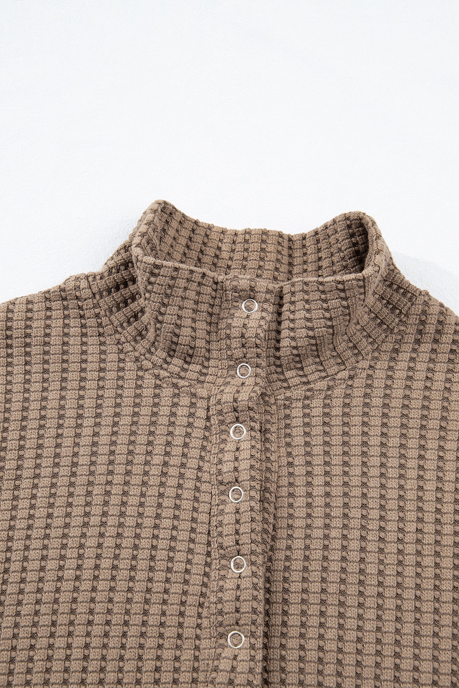 Woman wearing a Mocha textured waffle knit pullover with snap collar, relaxed long sleeves, and ribbed cuffs with white pants.