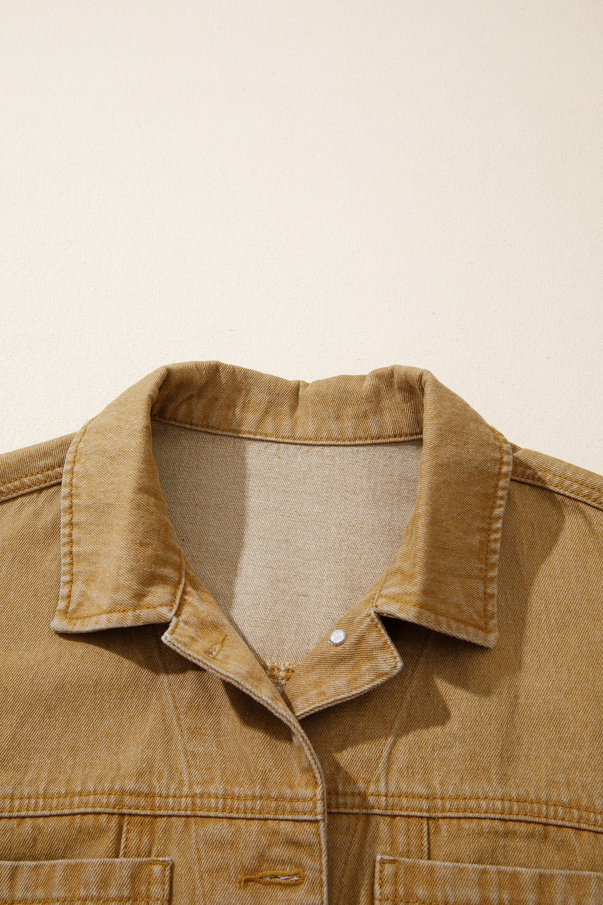 Tan women's denim jacket with metal button front, collared neckline, long sleeves, patch pockets, and relaxed fit.