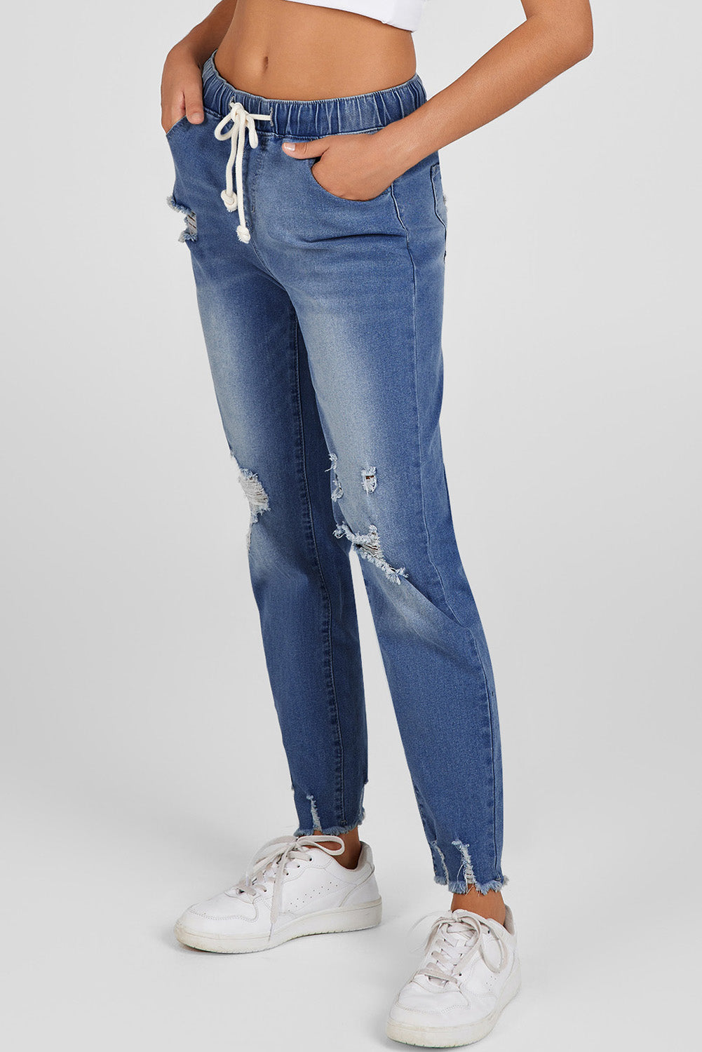 Medium wash blue distressed slim straight leg jeans with drawstring elastic waist and raw hem
