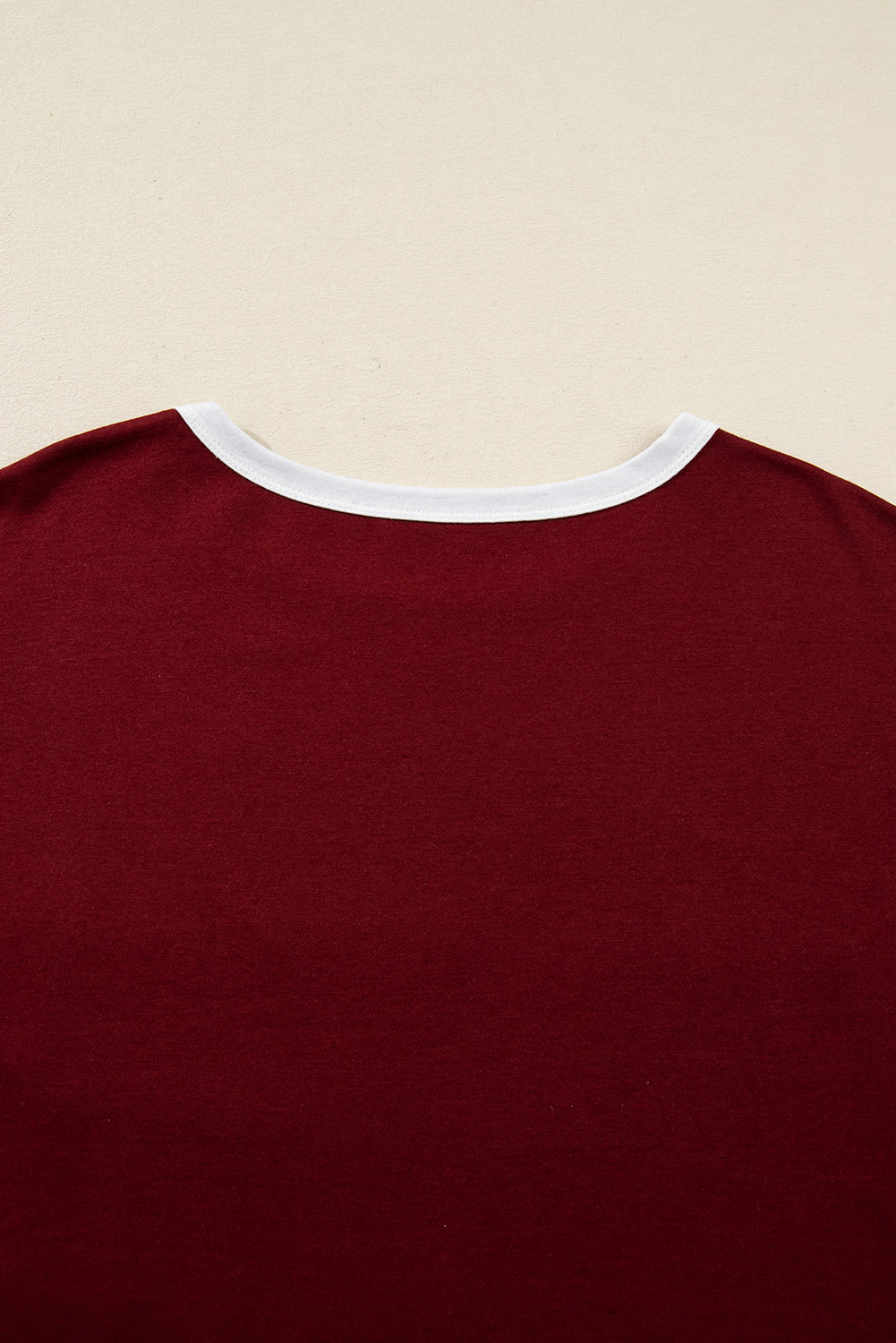 Red Dahlia women’s long sleeve top with round white contrast neckline, white sleeve bands, oversized daisy patch front, and relaxed shift silhouette.