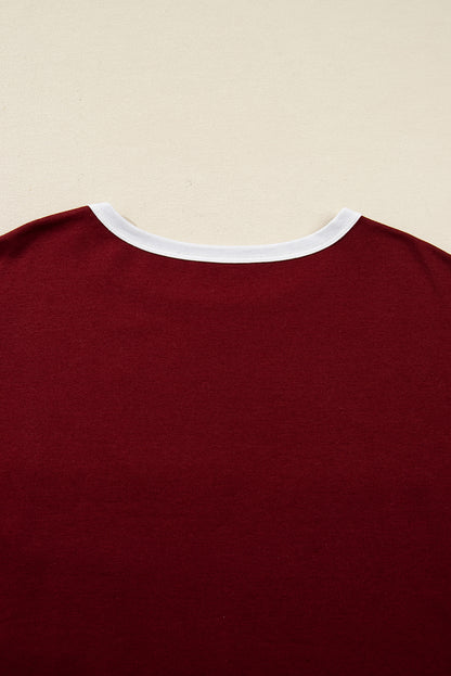 Red Dahlia women’s long sleeve top with round white contrast neckline, white sleeve bands, oversized daisy patch front, and relaxed shift silhouette.