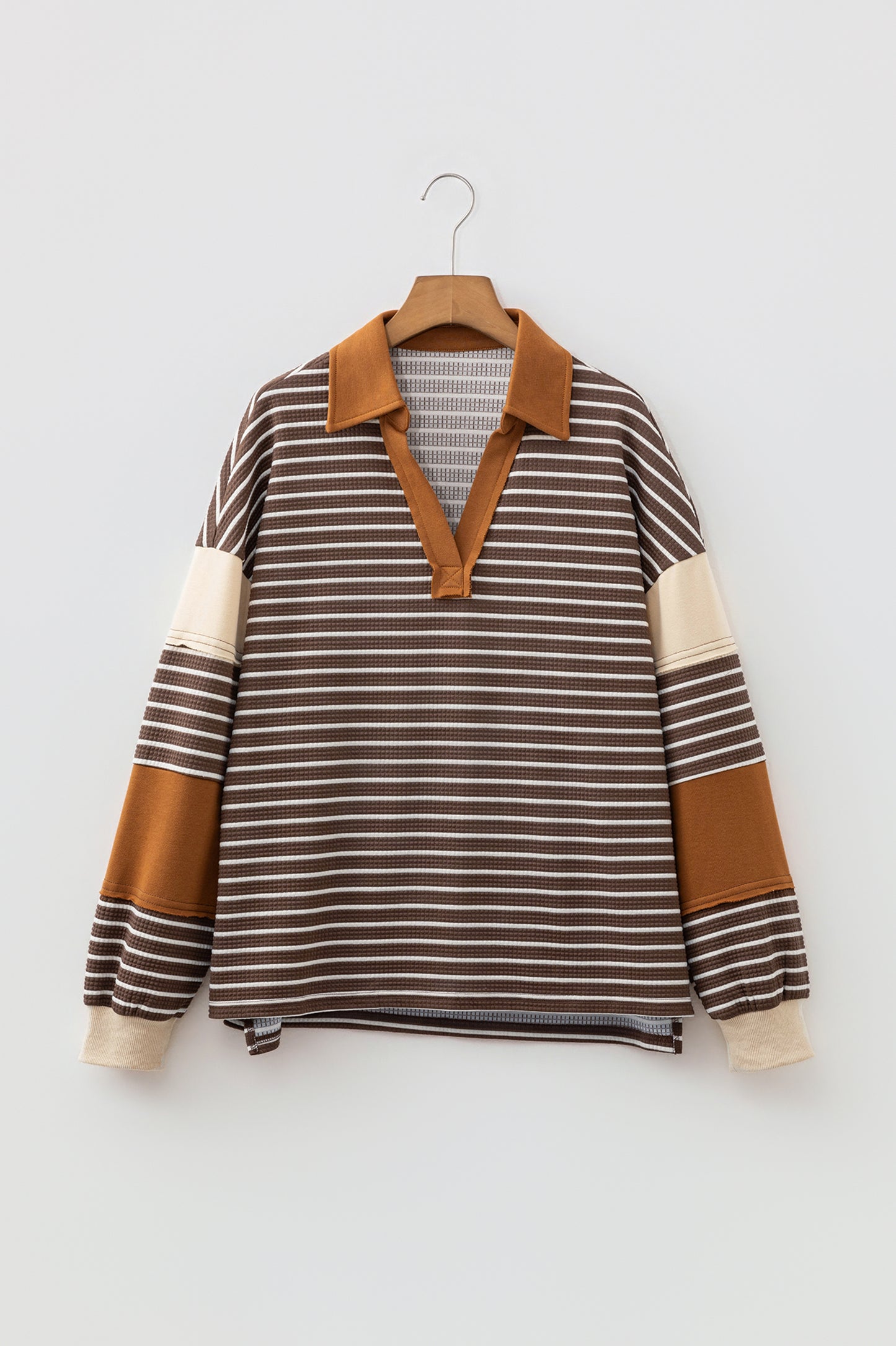 Cocoa Caramel and ivory striped colorblock pullover with a collared V-neckline, dropped shoulders, and long paneled sleeves.