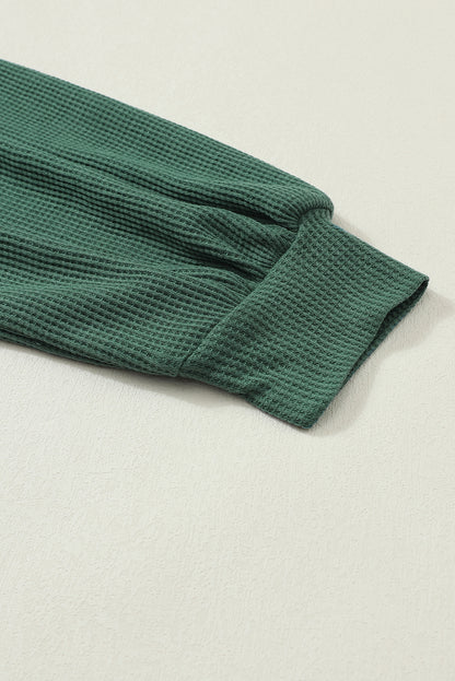 Forest green waffle knit long sleeve top with floral lace shoulder panels, crew neckline, relaxed fit, and balloon sleeves.