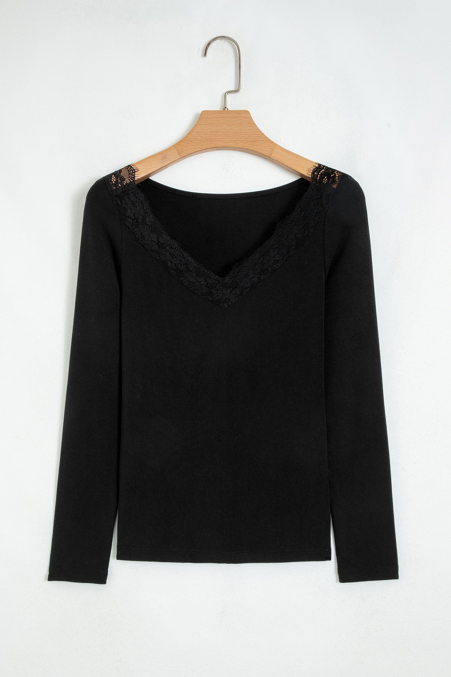 Black fitted long sleeve top with floral lace-trim V-neckline and soft stretch fabric styled with white pants.