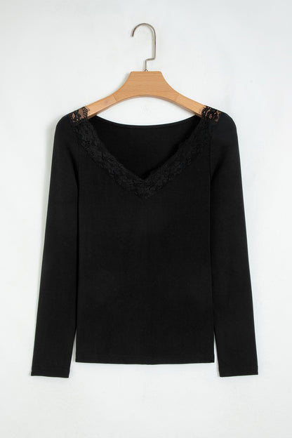 Black fitted long sleeve top with floral lace-trim V-neckline and soft stretch fabric styled with white pants.