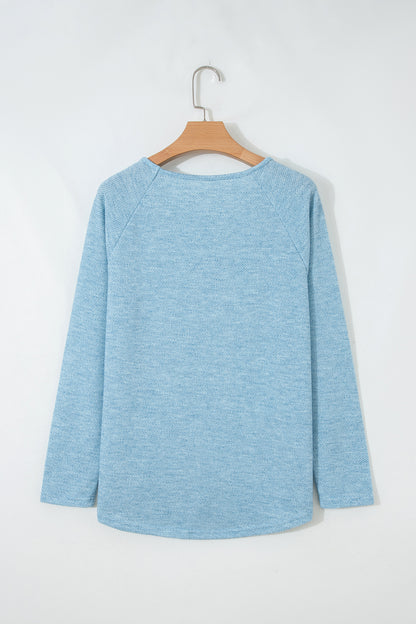 Powder Blue textured raglan long sleeve top with round neckline, relaxed fit, and curved hem
