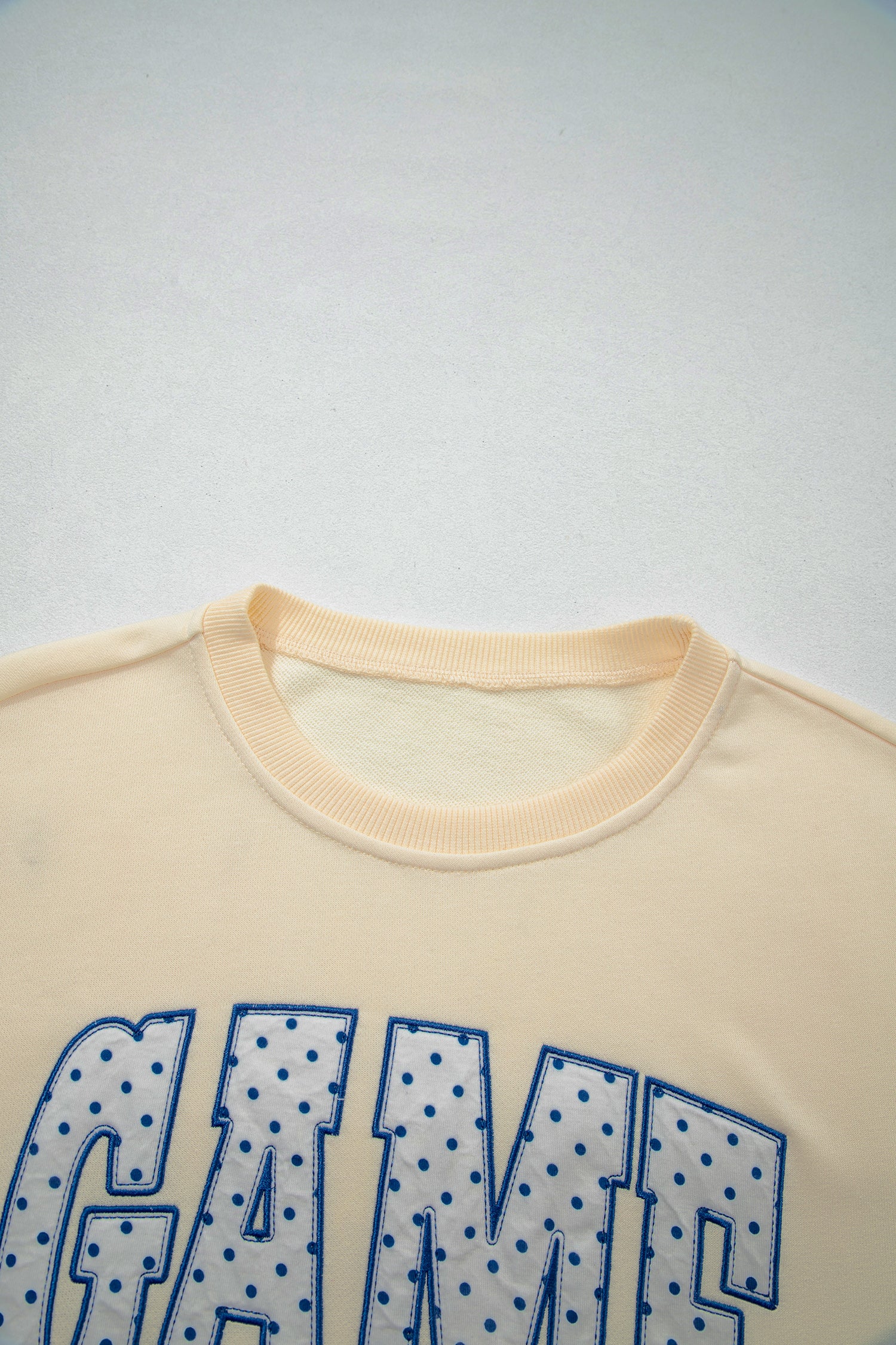 Cream Game Day embroidered sweatshirt and matching drawstring shorts set featuring long sleeves, blue contrast trim, relaxed fit, and casual sporty style.
