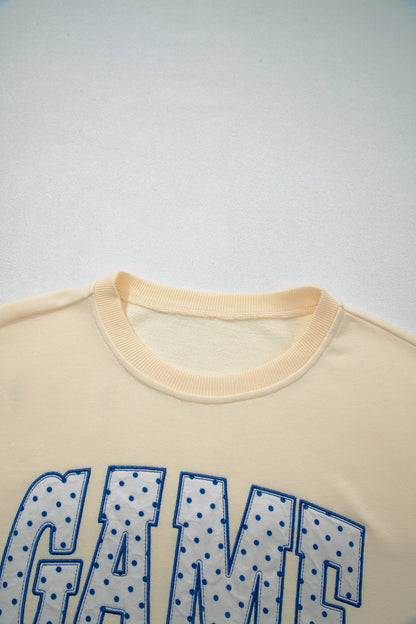 Cream Game Day embroidered sweatshirt and matching drawstring shorts set featuring long sleeves, blue contrast trim, relaxed fit, and casual sporty style.
