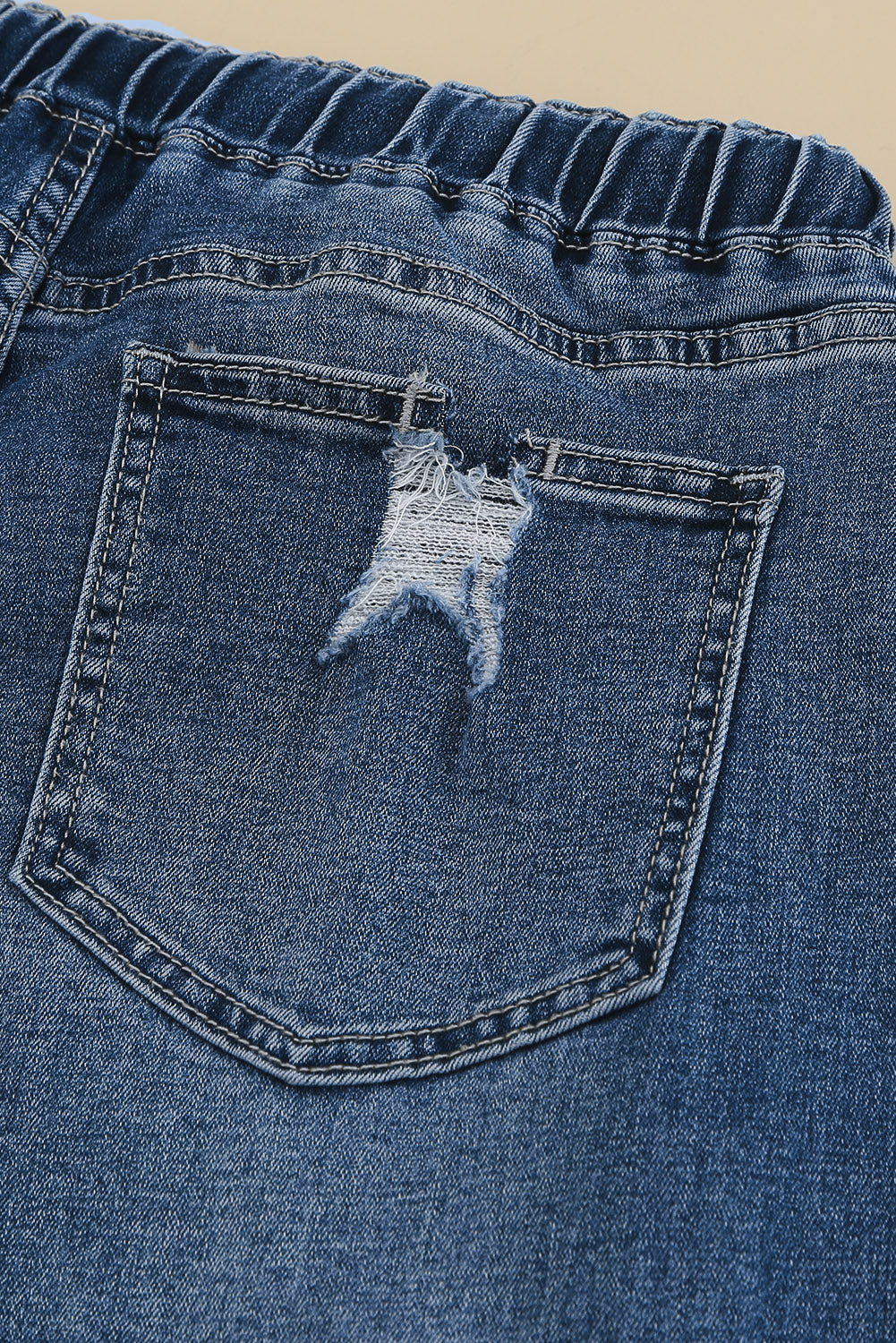 Medium wash blue distressed slim straight leg jeans with drawstring elastic waist and raw hem
