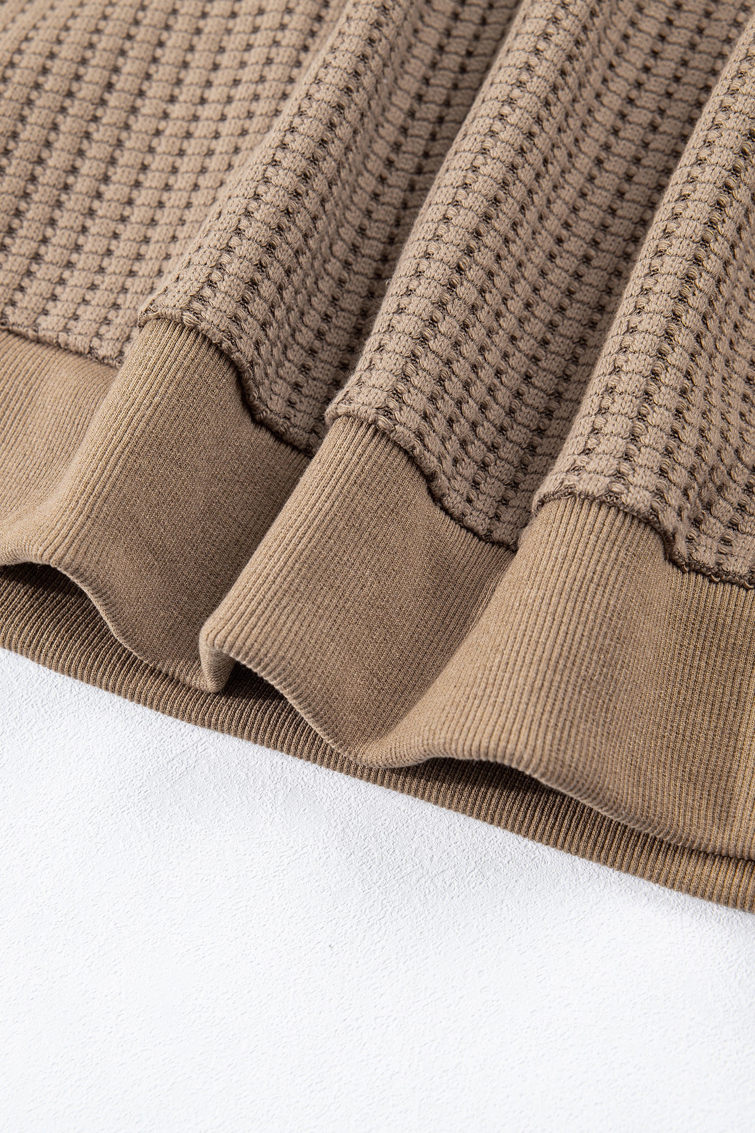 Woman wearing a Mocha textured waffle knit pullover with snap collar, relaxed long sleeves, and ribbed cuffs with white pants.