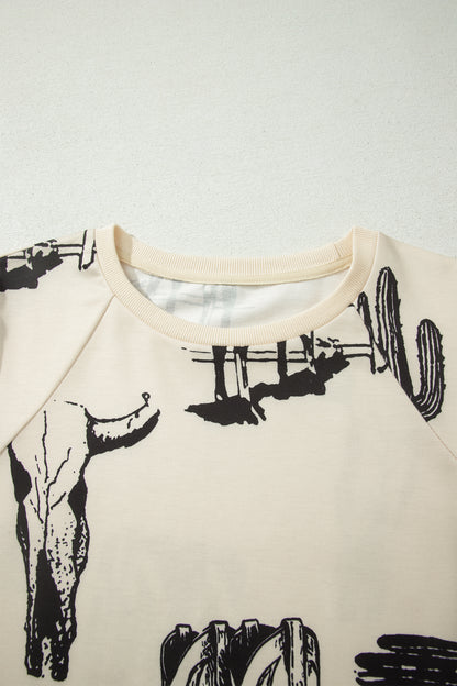 Cream Western graphic print top with crew neckline, short sleeves with gathered armholes, and black cowboy boot, cactus, horseshoe, and Southwestern motifs.