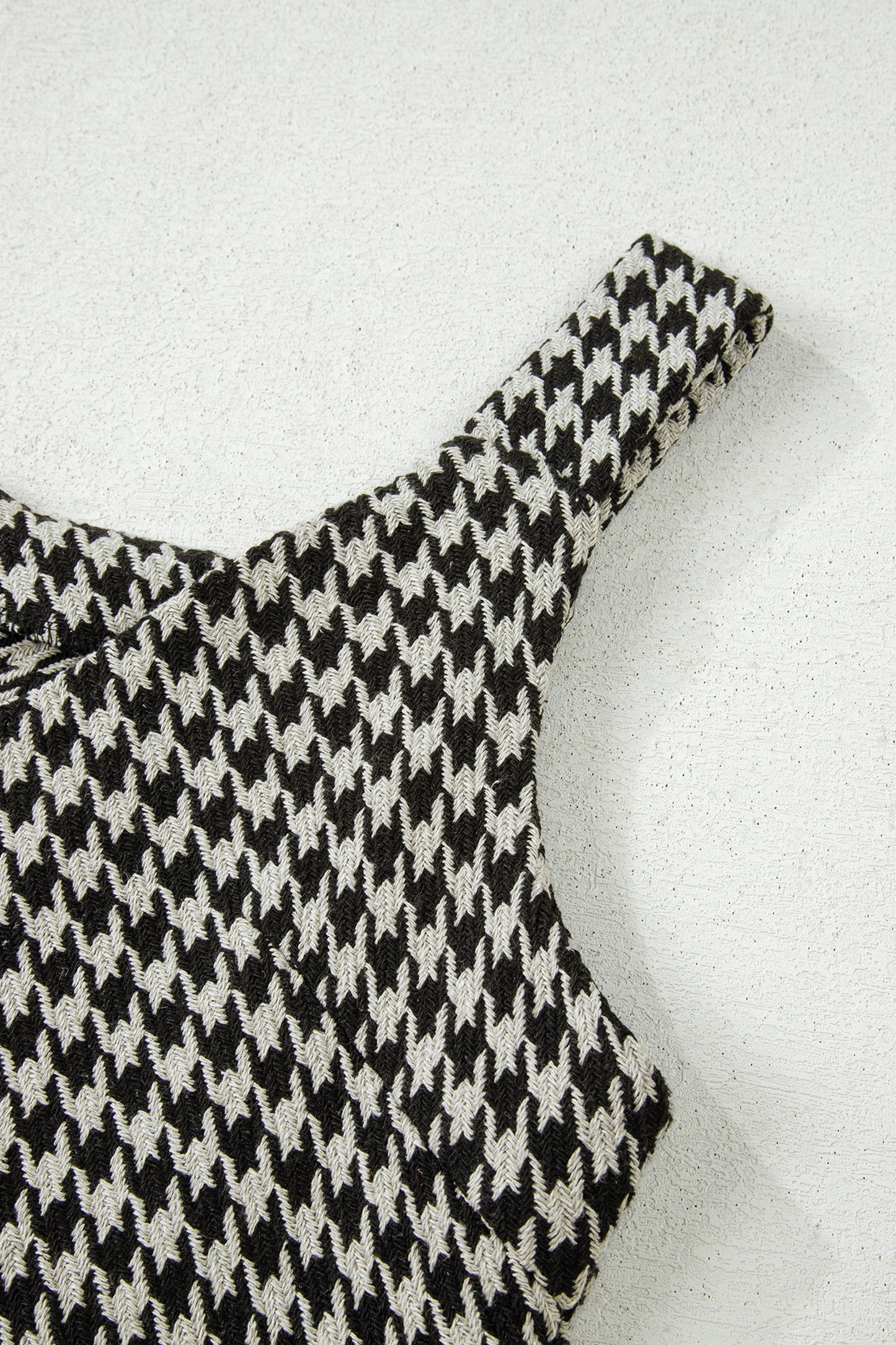 Black textured houndstooth jacquard sleeveless mini dress with V-neckline and A-line silhouette.