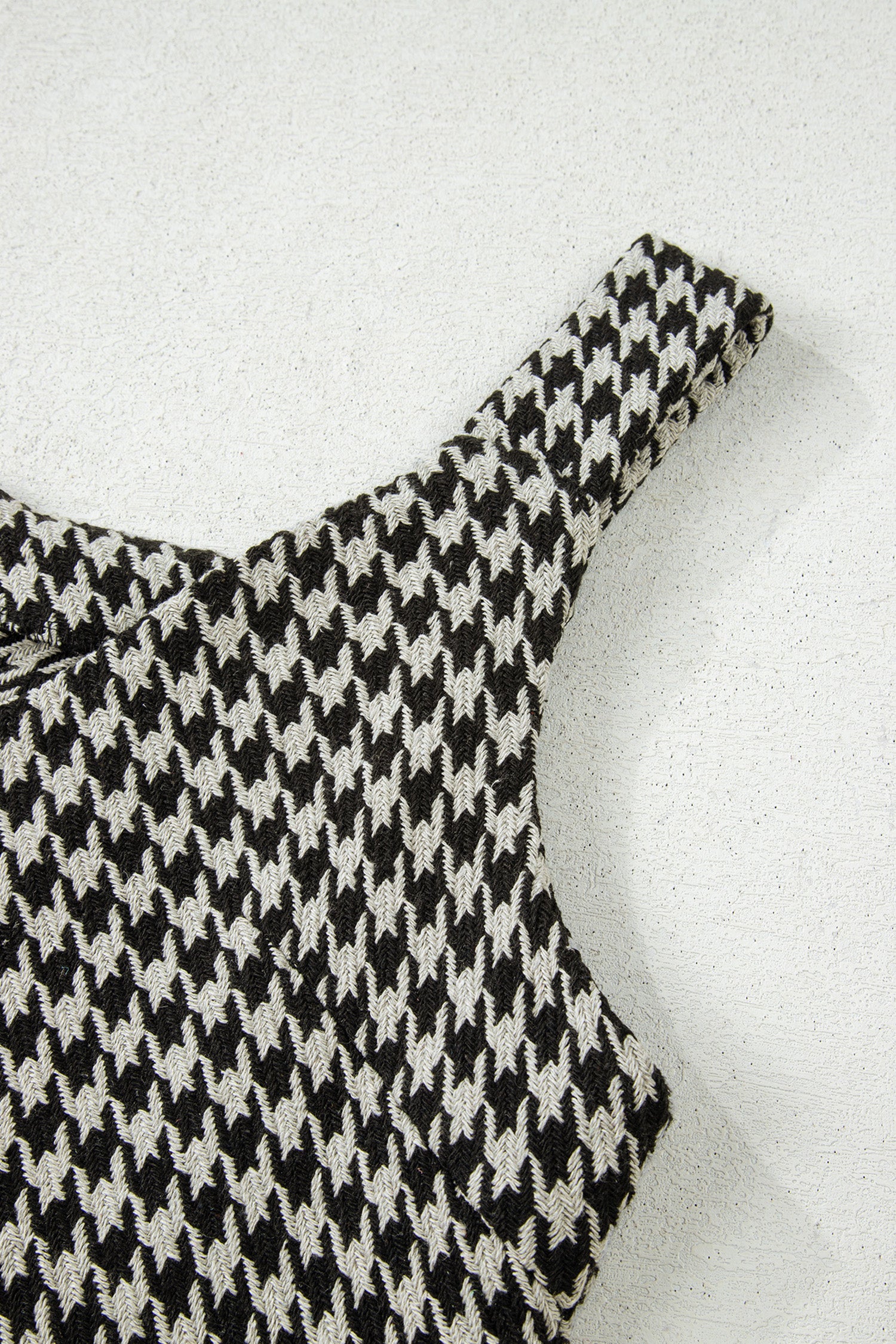 Black textured houndstooth jacquard sleeveless mini dress with V-neckline and A-line silhouette.