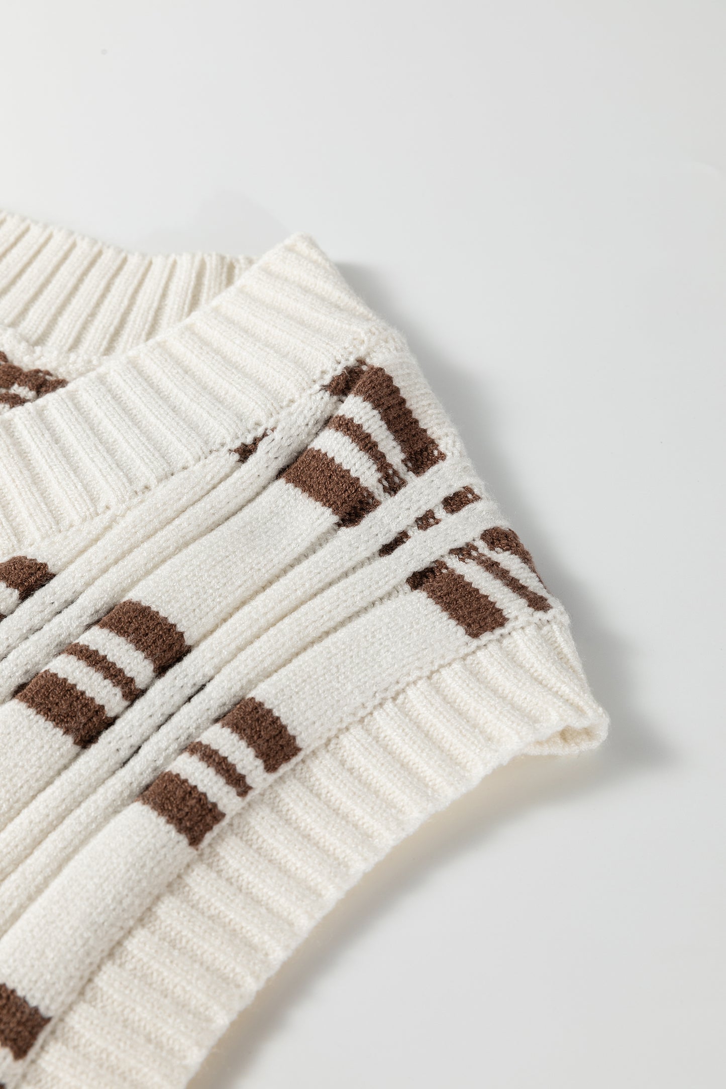 Oatmeal knit sweater vest with brown striped pattern, V-neckline, sleeveless design, and ribbed trim.