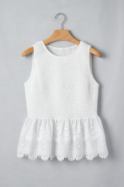 Women's white smocked sleeveless peplum top with embroidered eyelet hem, round neckline, textured bodice, and feminine boutique style.