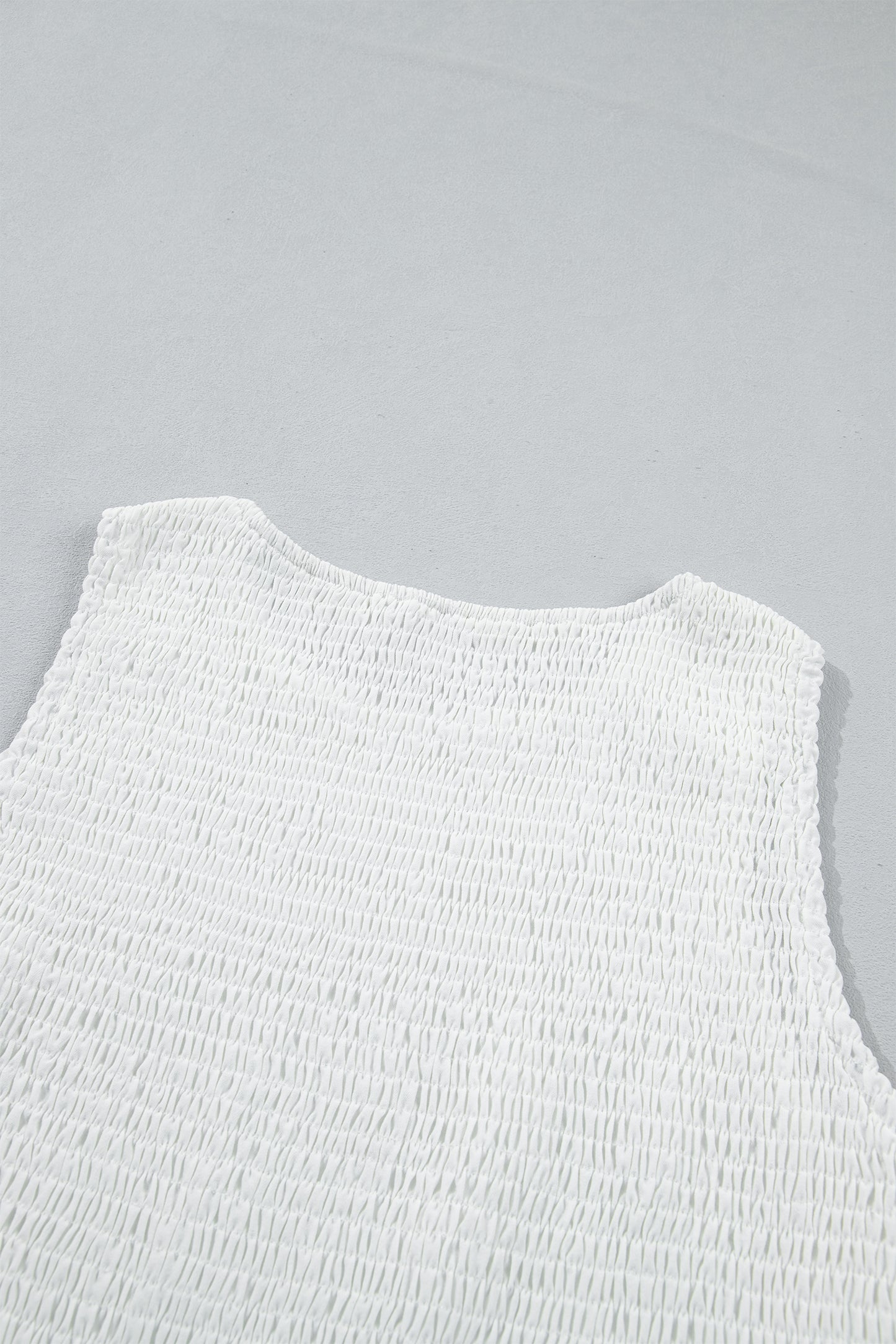 Women's white smocked sleeveless peplum top with embroidered eyelet hem, round neckline, textured bodice, and feminine boutique style.
