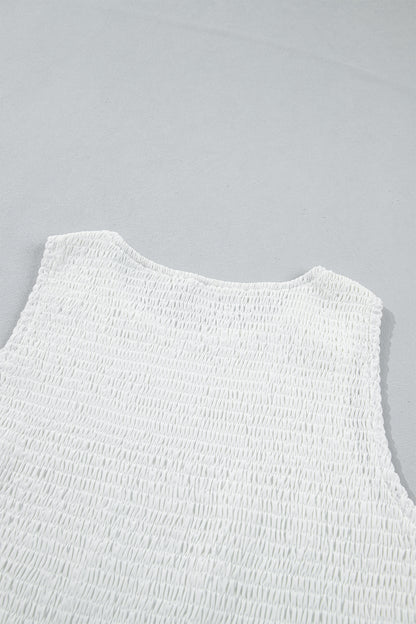 Women's white smocked sleeveless peplum top with embroidered eyelet hem, round neckline, textured bodice, and feminine boutique style.
