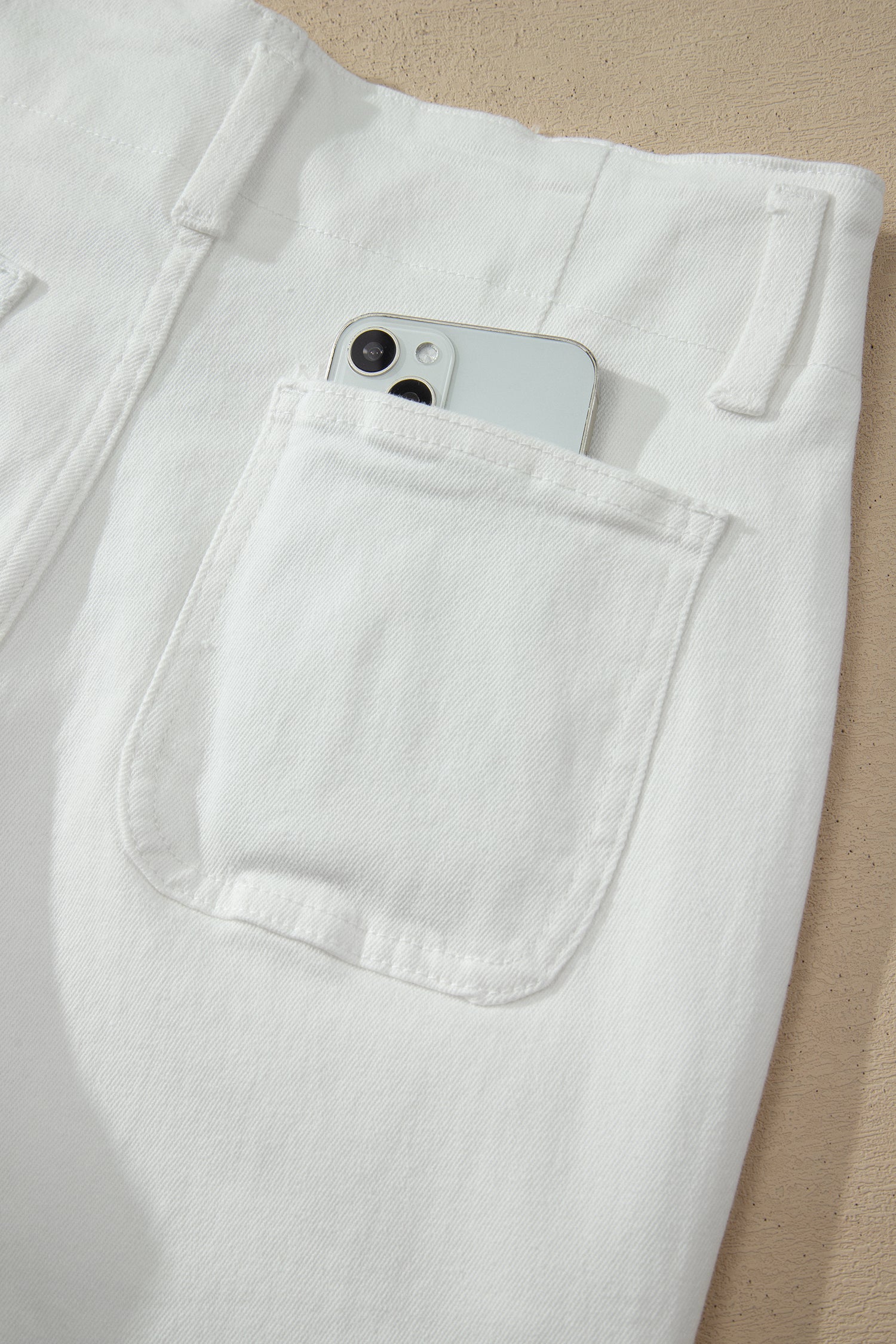 White high rise wide leg jeans with double-button waistband, front pockets and cropped hem.