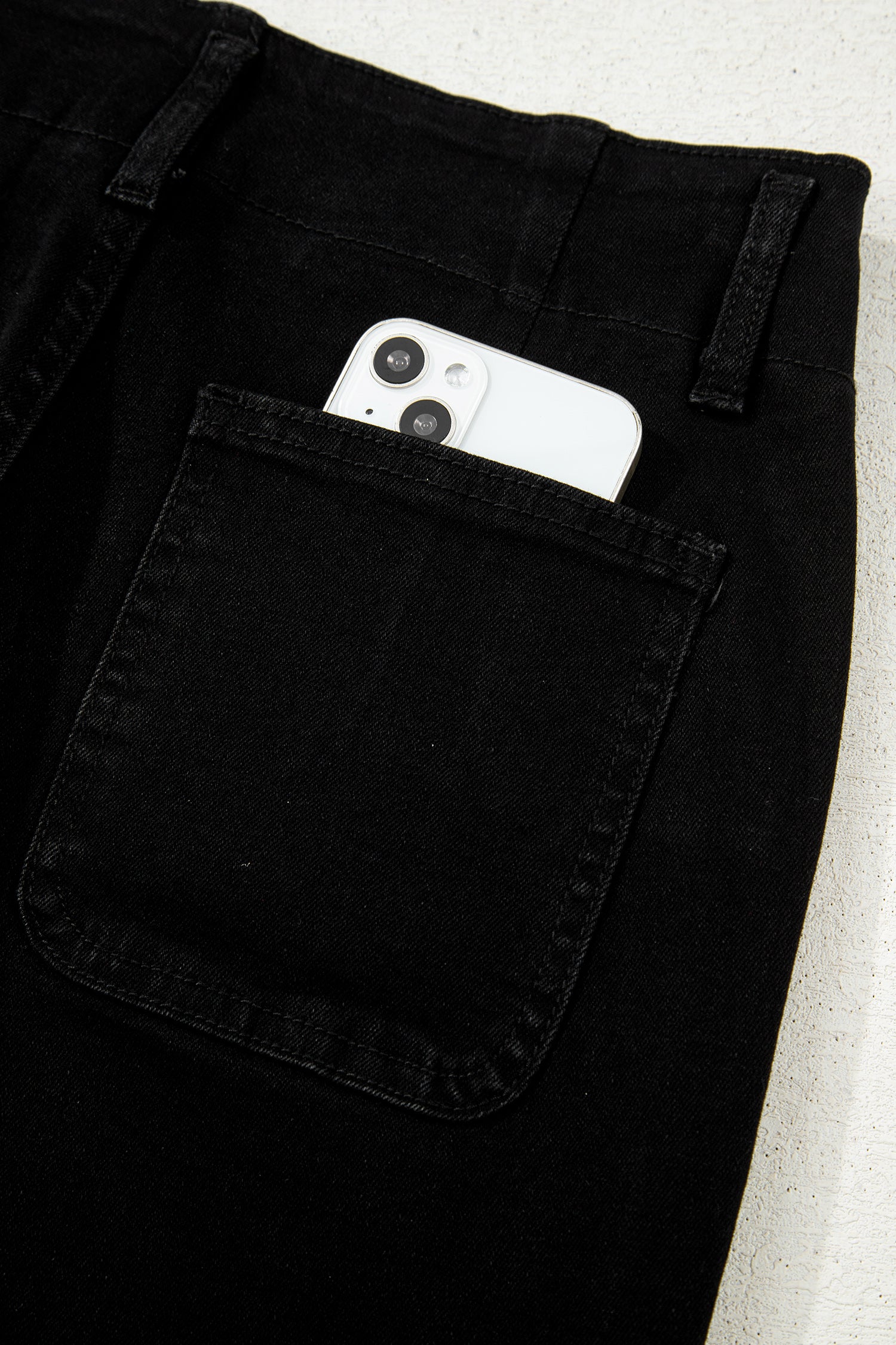 Black high rise wide leg jeans with double-button waistband, front pockets and cropped hem.