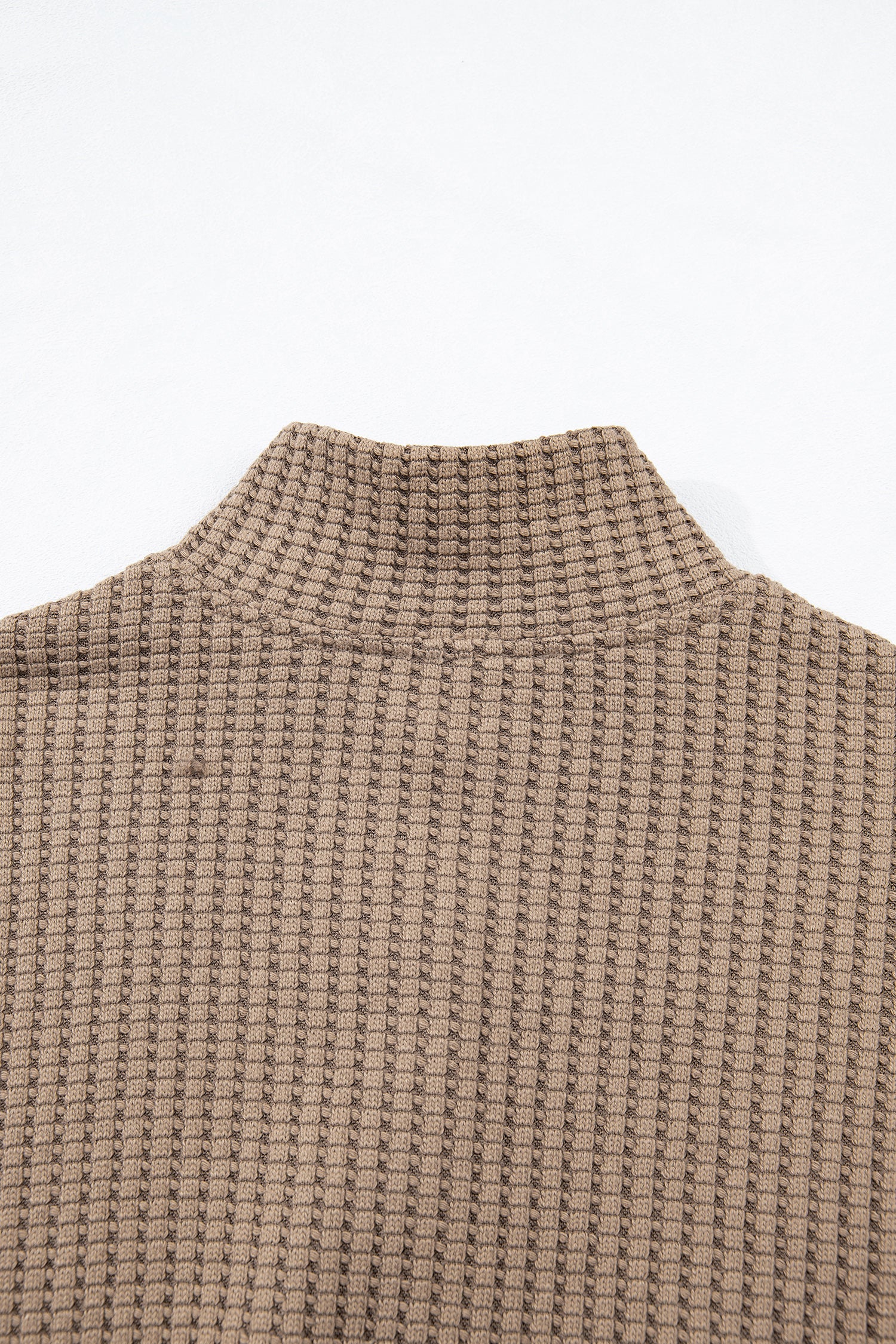 Woman wearing a Mocha textured waffle knit pullover with snap collar, relaxed long sleeves, and ribbed cuffs with white pants.