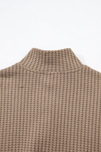 Woman wearing a Mocha textured waffle knit pullover with snap collar, relaxed long sleeves, and ribbed cuffs with white pants.